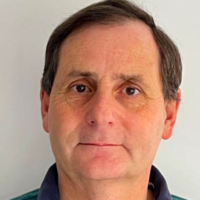 Middle-aged man with short brown hair, wearing a green collared shirt, facing the camera with a neutral expression.